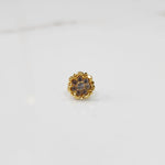 Close-up of gold ring featuring rounded petals with pink gemstones
