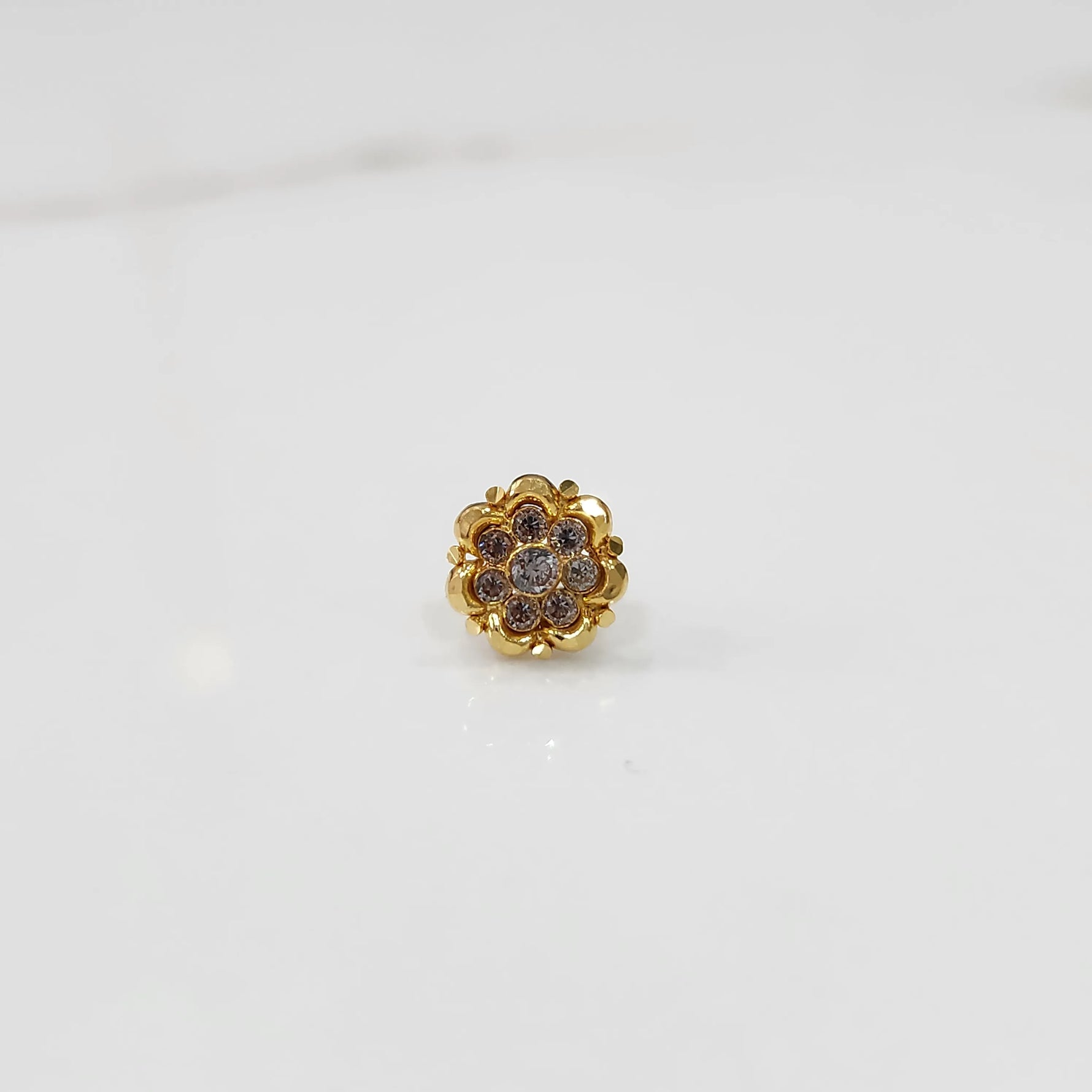 Close-up of gold ring featuring rounded petals with pink gemstones