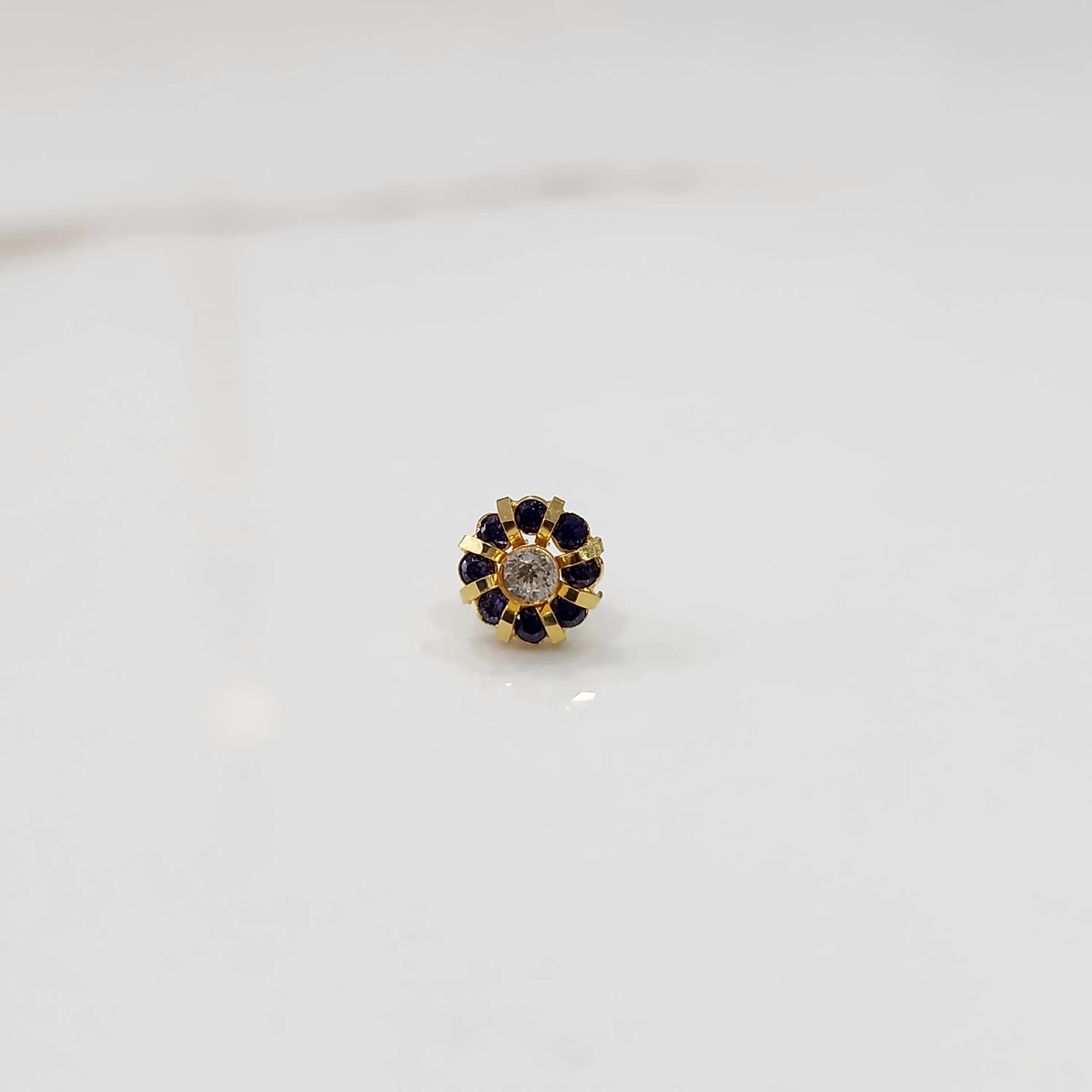 Top view of gold ring with clear center stone and purple petal stones