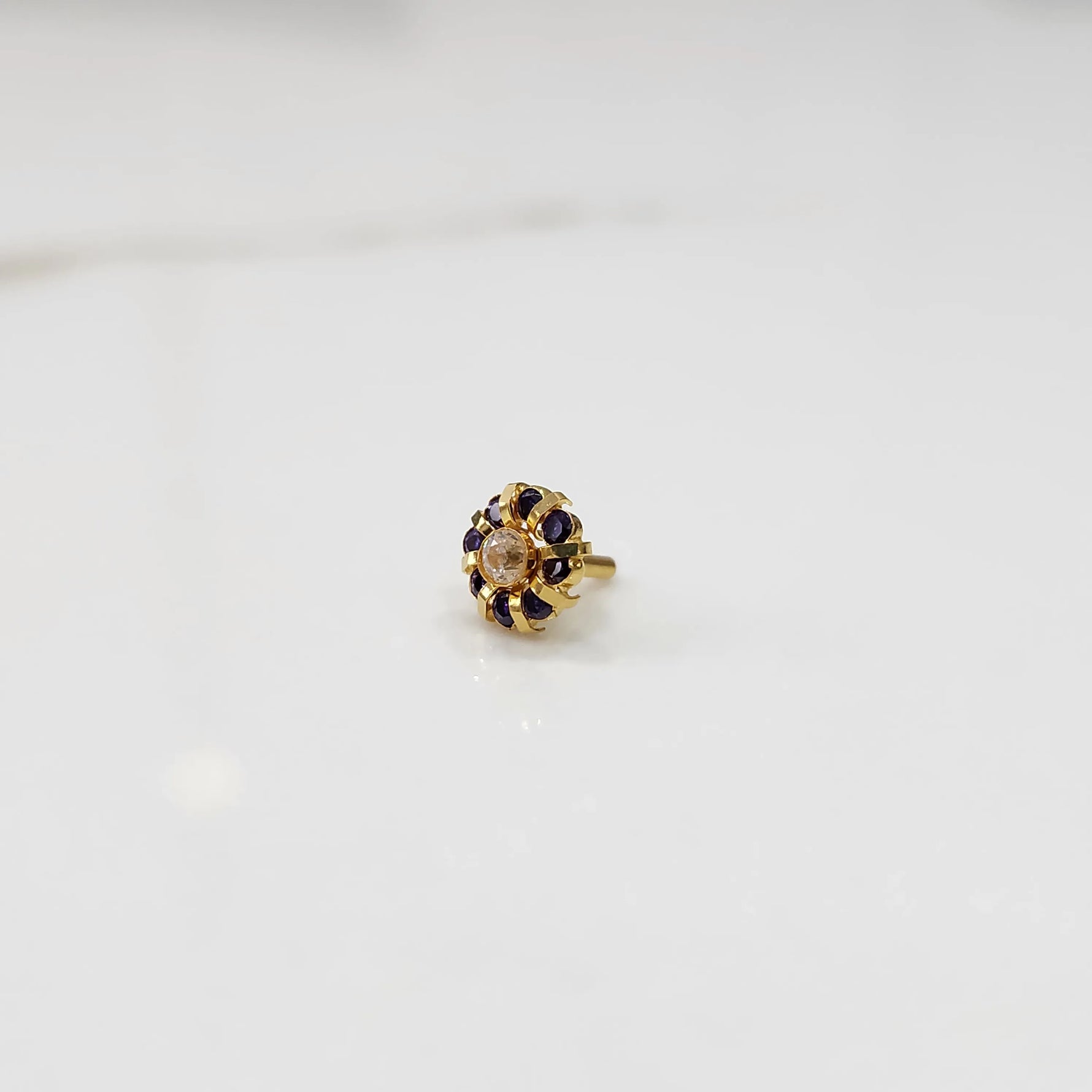 Gold ring with sculpted petal design and clear center with purple stones