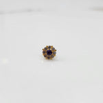 Top view of gold ring with purple center stone and petal design