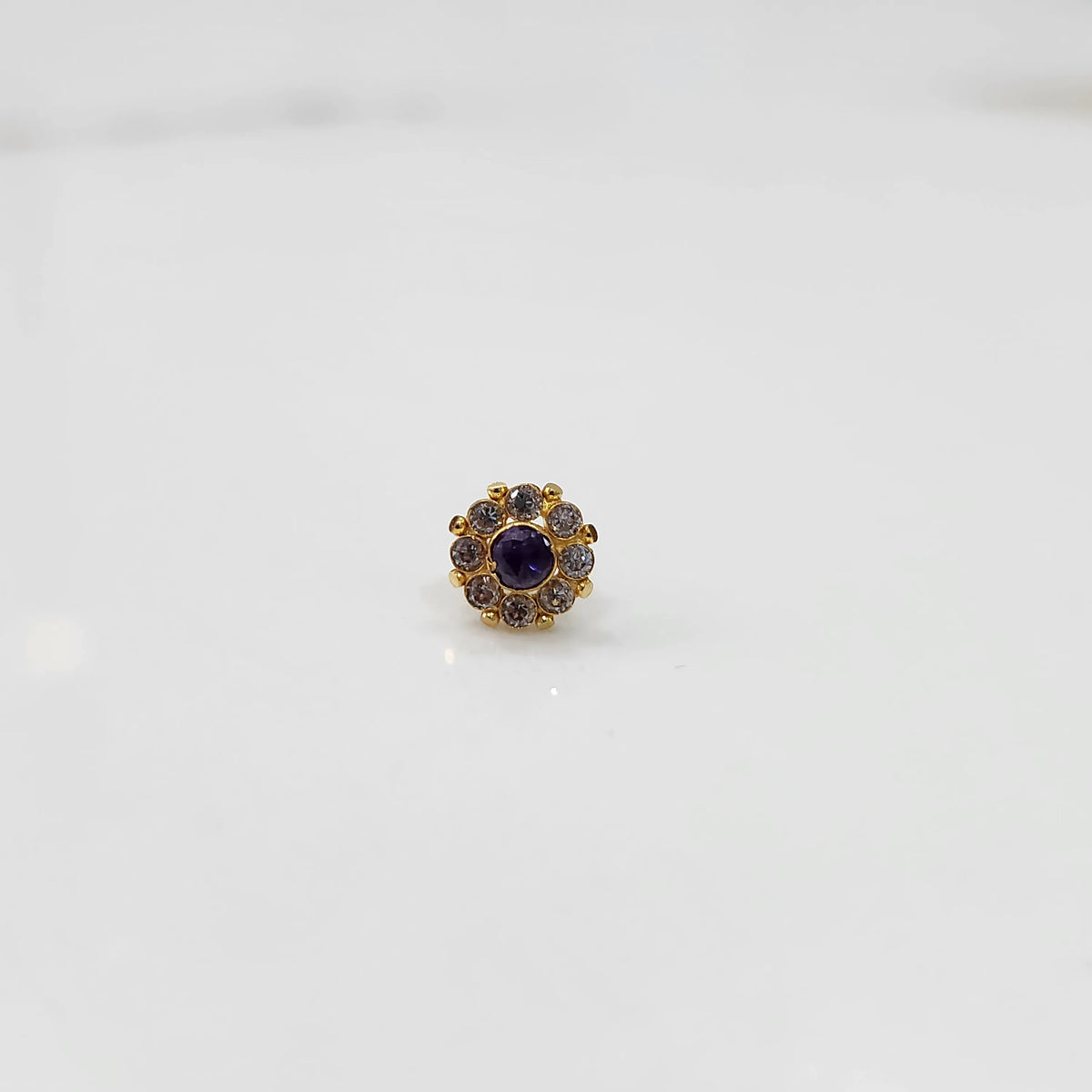 Top view of gold ring with purple center stone and petal design