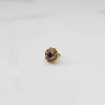 Gold ring with sculpted petal design and purple stone accent