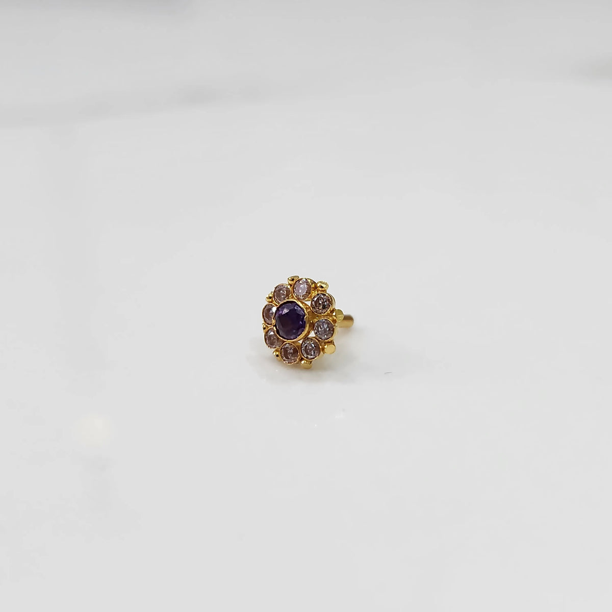 Gold ring with sculpted petal design and purple stone accent