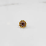 Top view of gold ring with ruby-red center stone and petal design