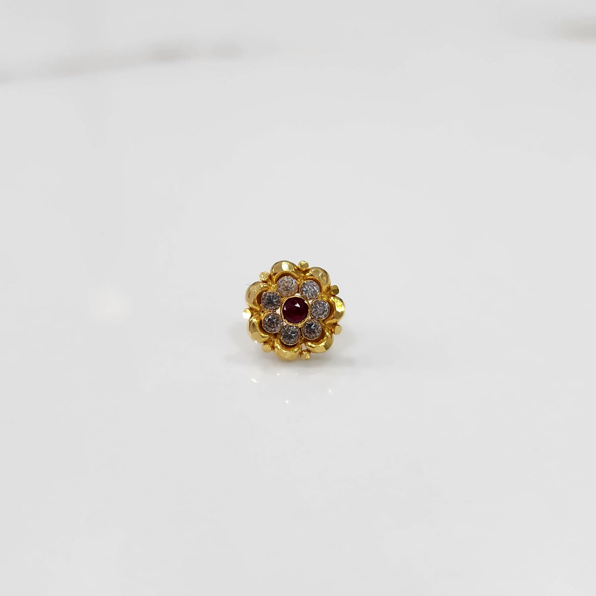 Top view of gold ring with ruby-red center stone and petal design