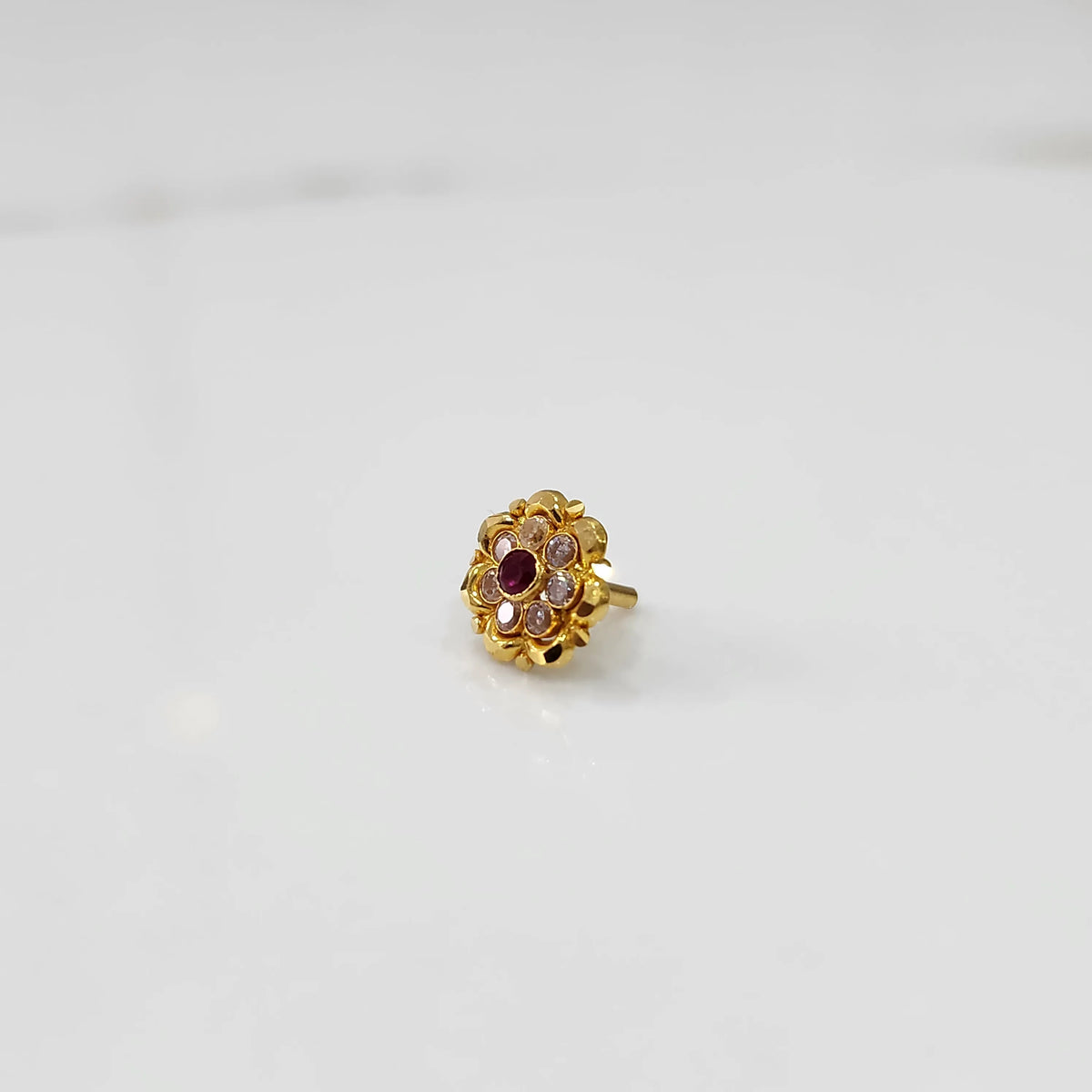 Traditional gold ring featuring rounded petals with red and champagne gemstones