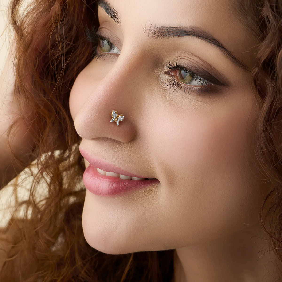 Woman wearing design of gold nose pin with delicate butterfly diamond style