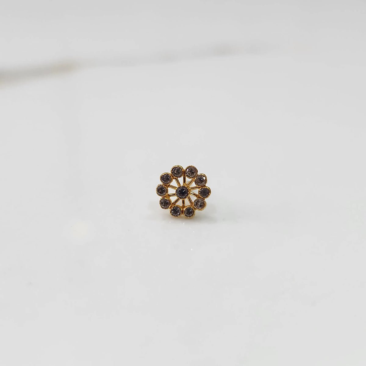 Front view of large gold nose pin with smoky-toned gemstone petals on white background