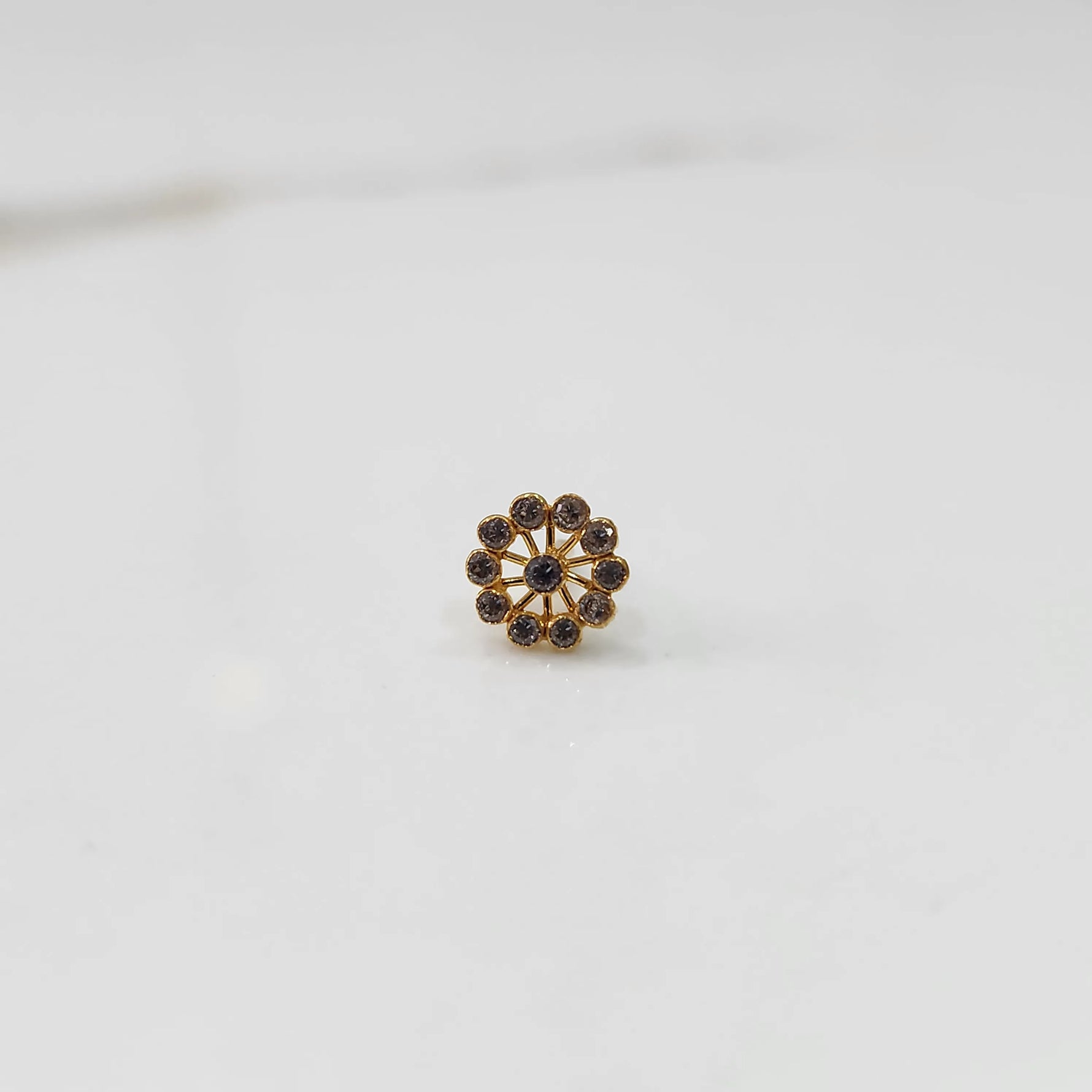 Front view of large gold nose pin with smoky-toned gemstone petals on white background