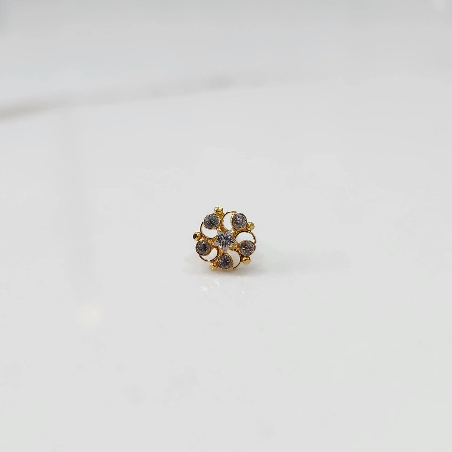 Gold nose pin with smoky-toned gemstone petals on white background
