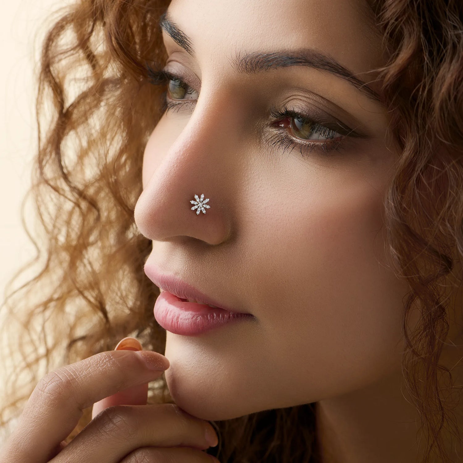 Woman wearing gold snowflake-shaped nose stud with white stones