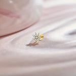 Gold snowflake-shaped stud with white stones on pink fabric
