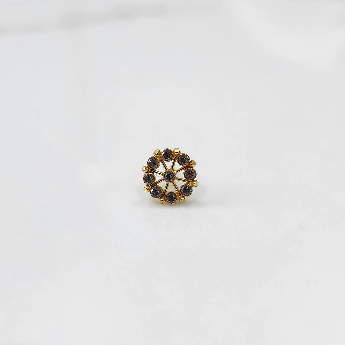 A gold star-shaped stud earring with champagne-colored stones set along the points, placed on a white background