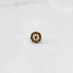 A gold star-shaped stud earring with champagne-colored stones set along the points, placed on a white background