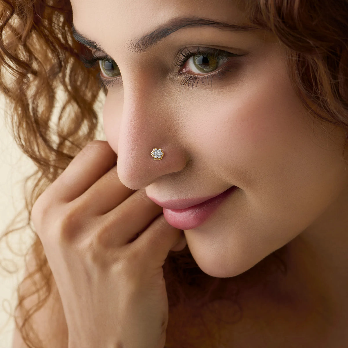 Close-up of woman wearing a gold nose stud with a six-petal blossom diamond design