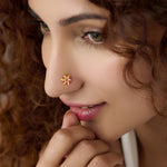Woman wearing gold star flower nose pin with pink stones