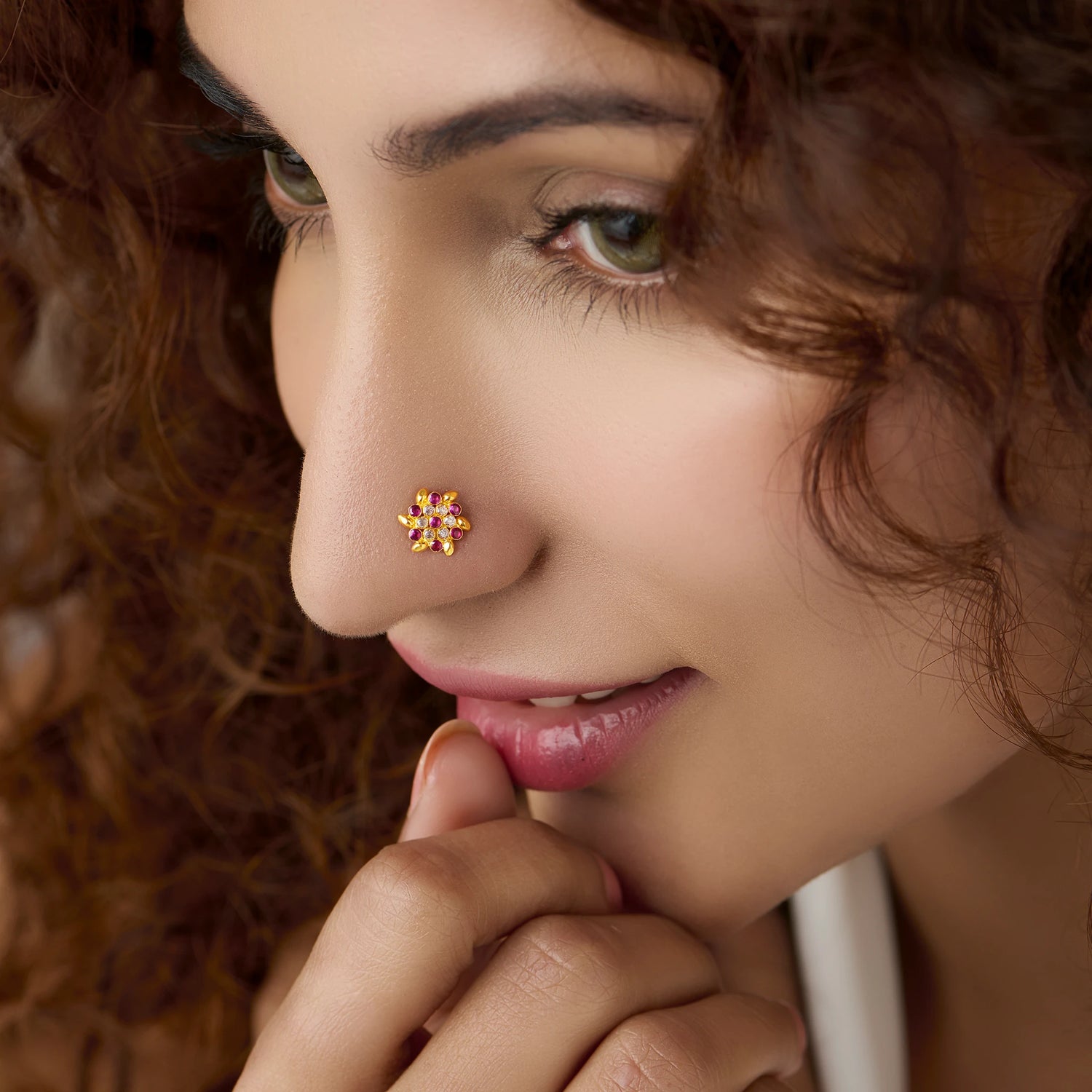 Woman wearing gold star flower nose pin with pink stones