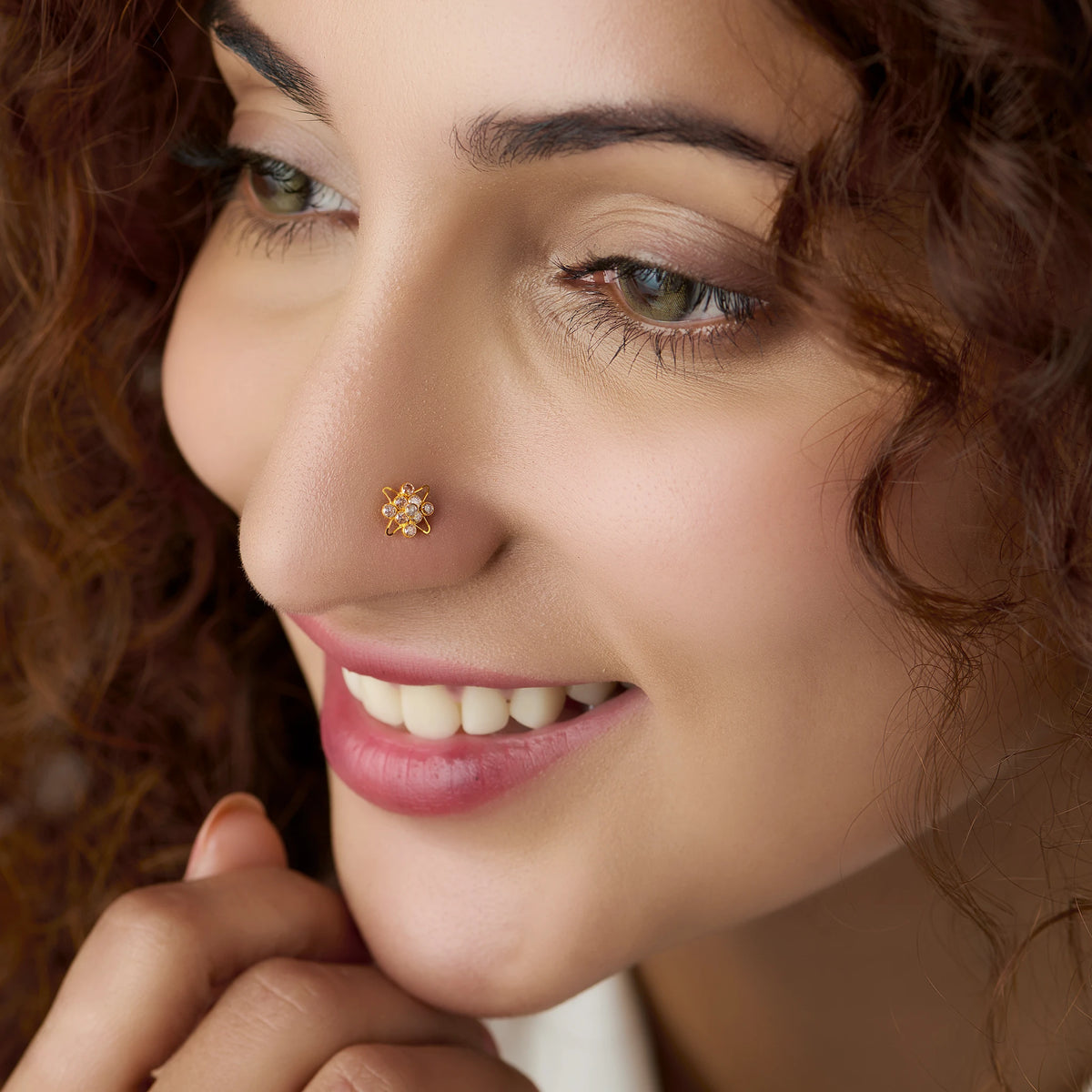 Woman wearing gold star flower nose pin with white stones