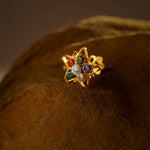 Nose pin design gold with multicolor floral gemstones on textured brown surface