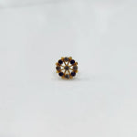 A gold star-frame stud earring with alternating purple and champagne-colored stones, placed on a white background