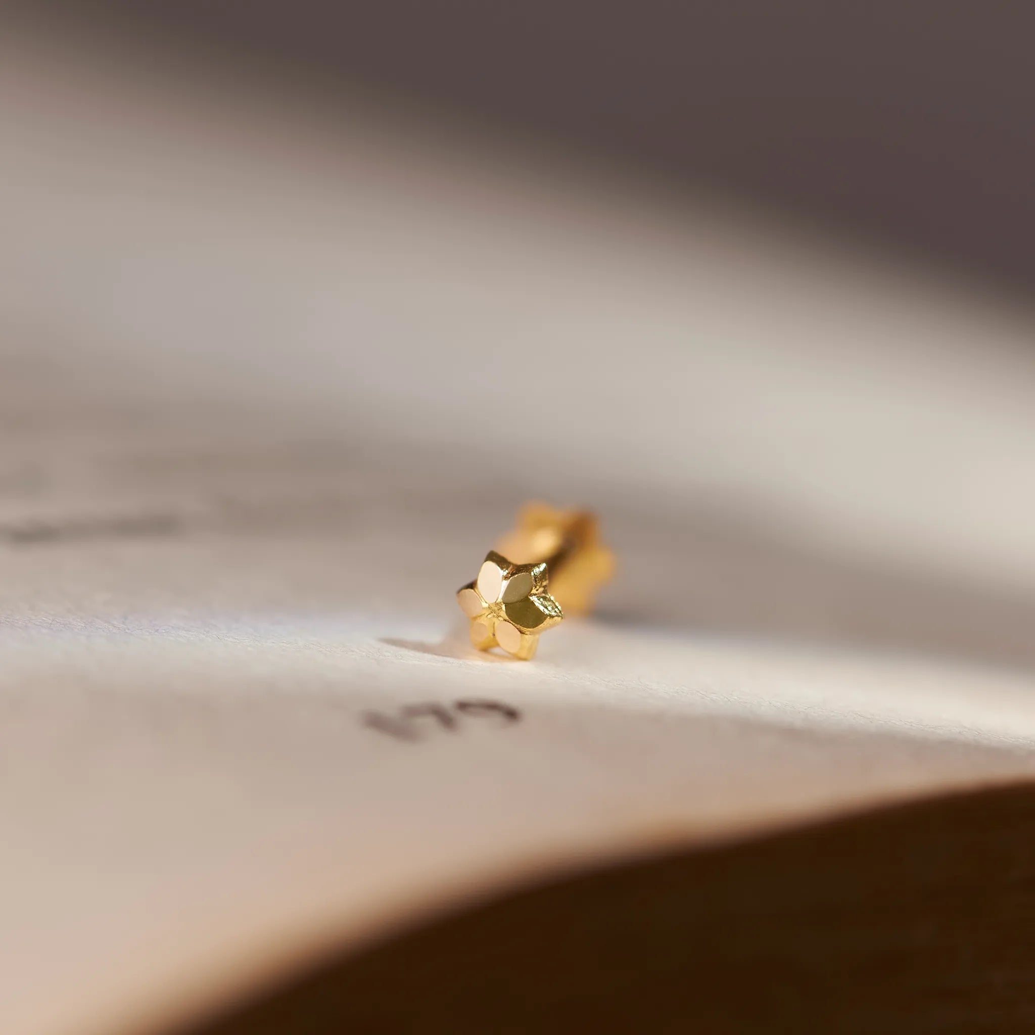Solid gold star-shaped stud earring, macro close-up shot