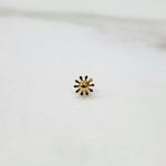 Gold nose pin in a sunflower or gear-shaped design on a white background