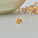 Gold flower-shaped stud earring with sunburst textured design