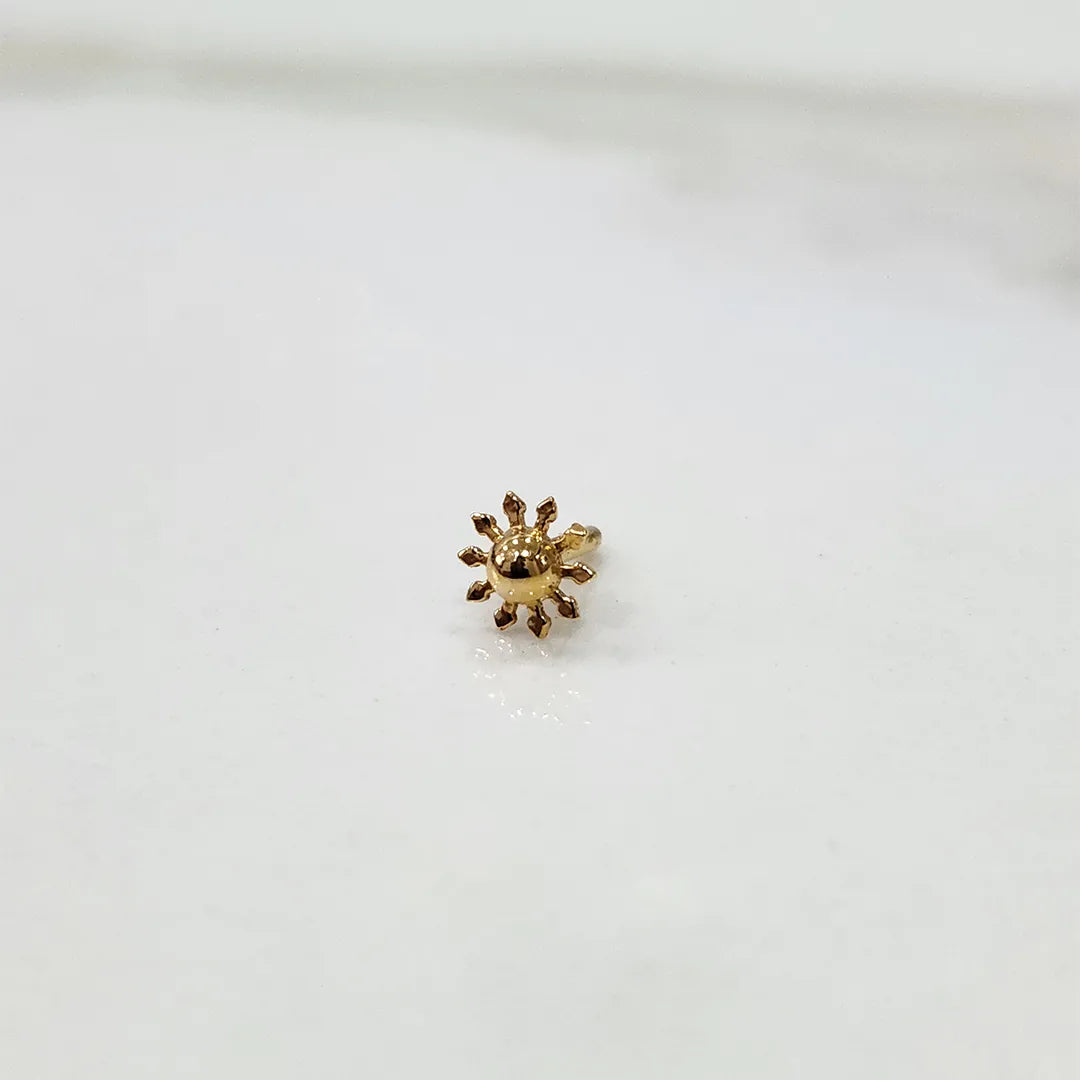 Close-up of a gold sunflower-shaped nose pin with screw-back fitting