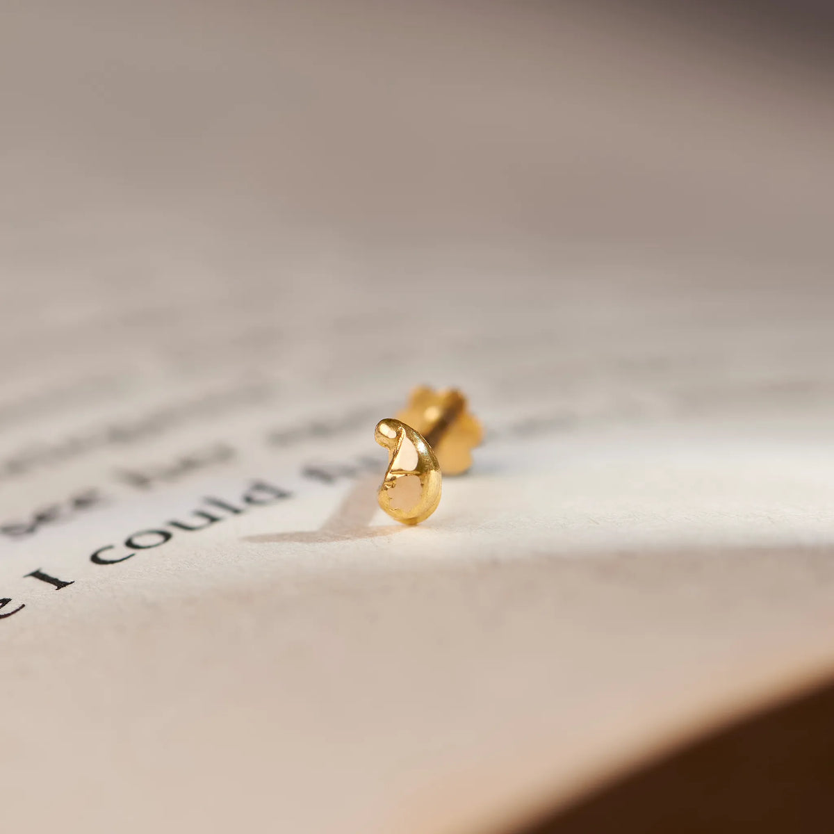 Gold swirl teardrop-shaped stud earring, close-up