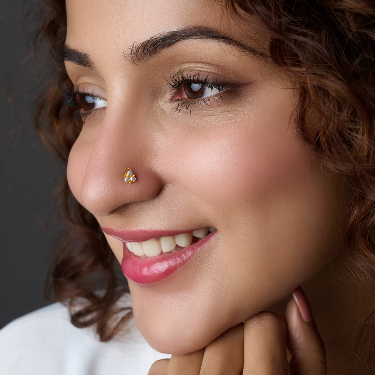 Woman wearing a teardrop gold nose pin with colored stones
