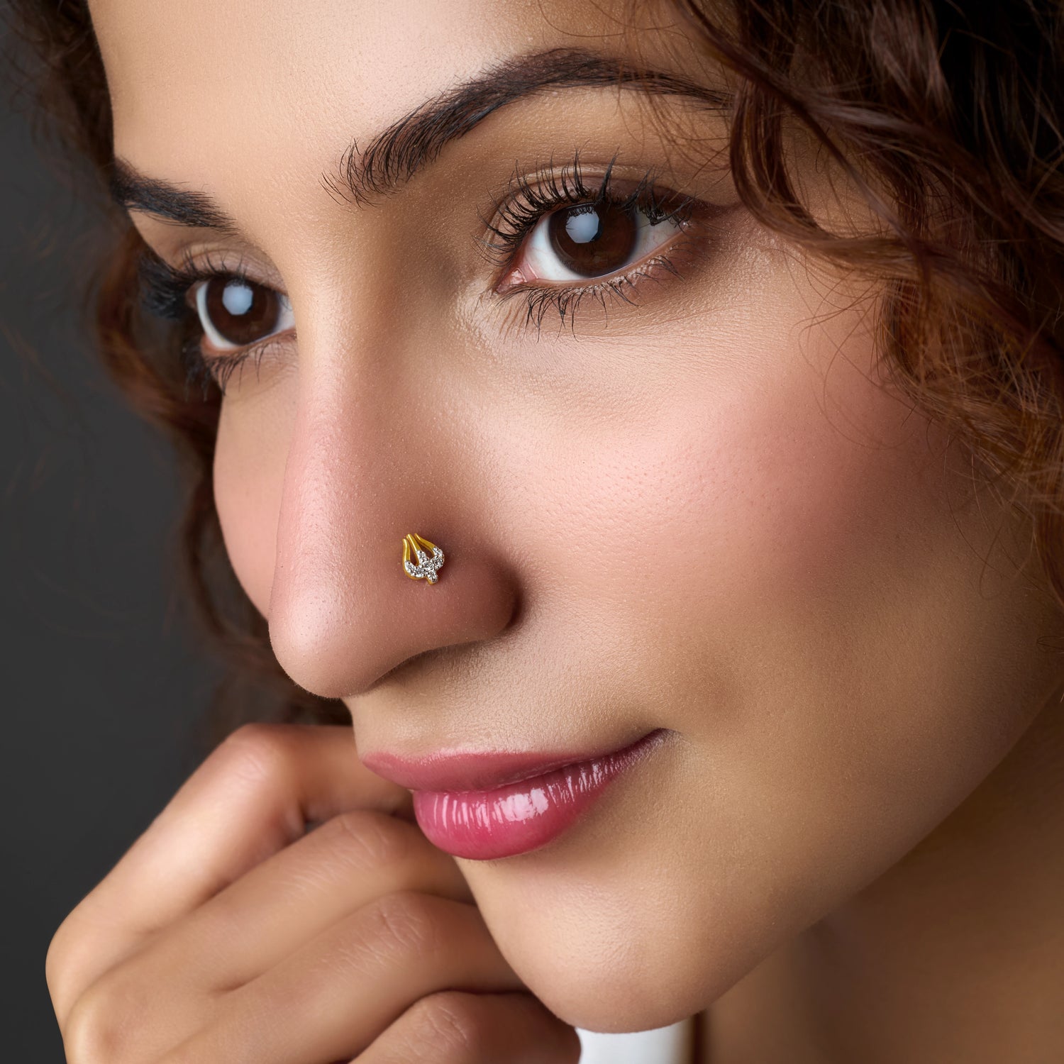 Woman wearing a teardrop-shaped gold nose pin