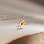 Gold droplet-style stud earring, close-up