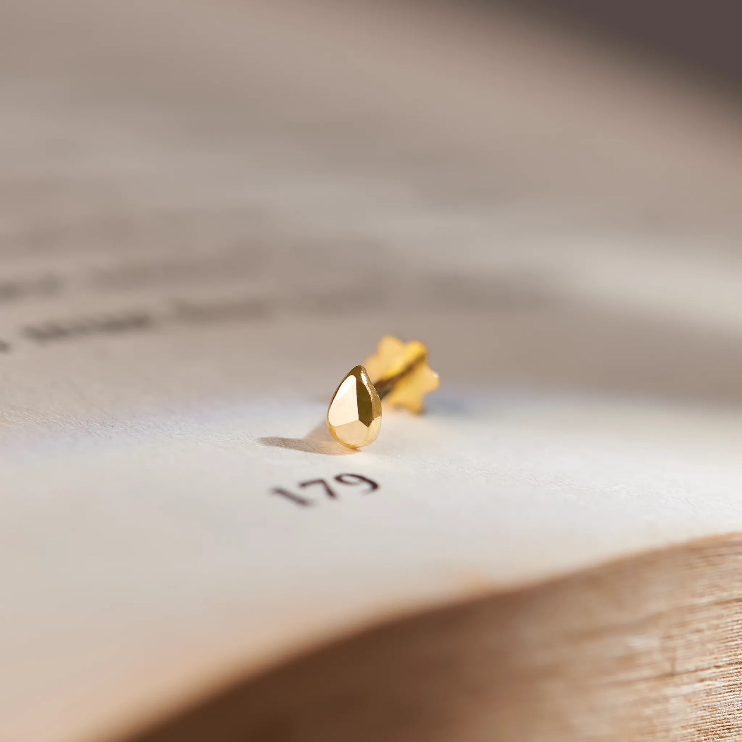 Gold droplet-style stud earring, close-up