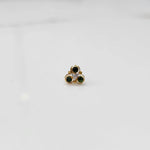 Close-up of gold three-stone ring featuring emerald and clear gemstones