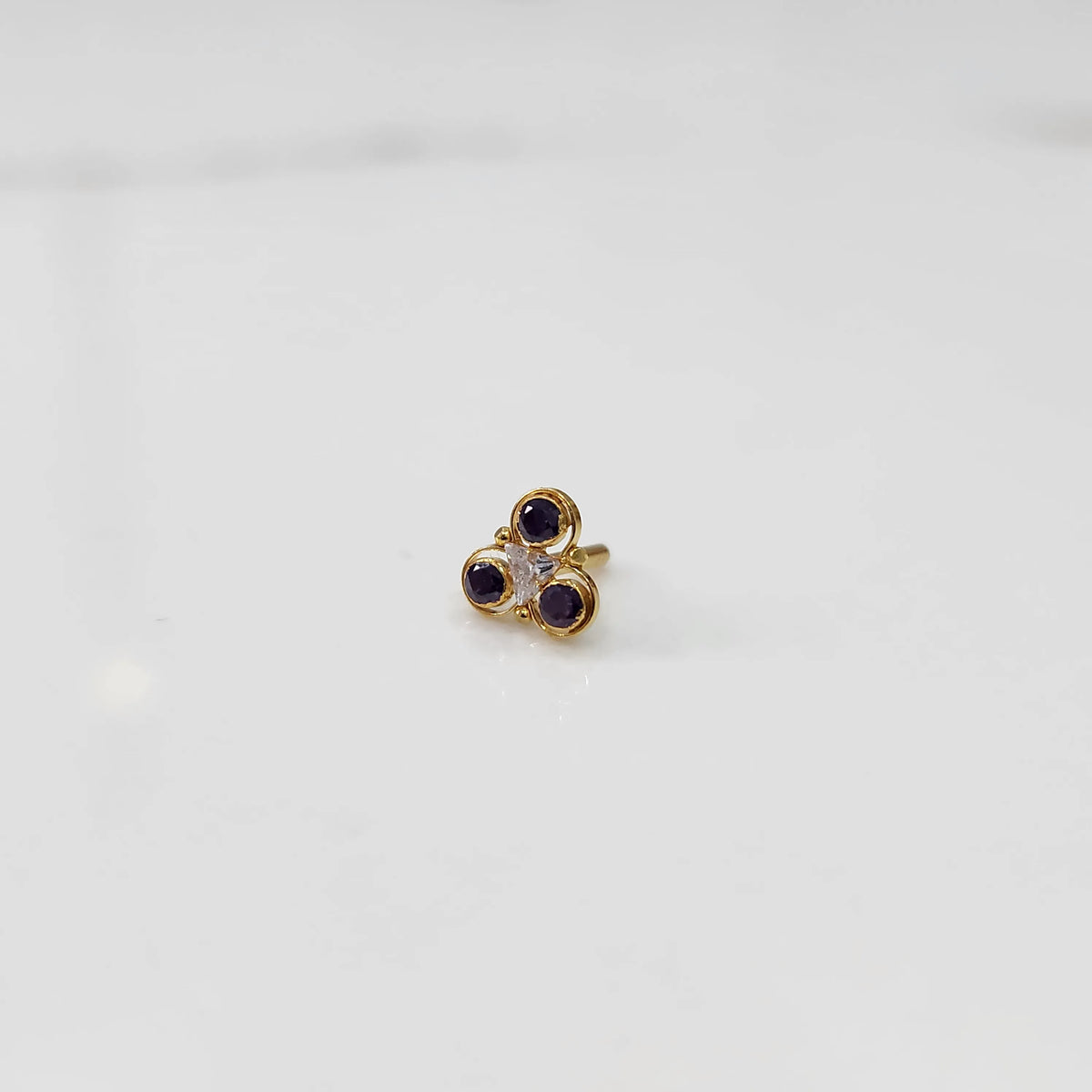 Gold ring with three-stone cluster in purple and clear stones