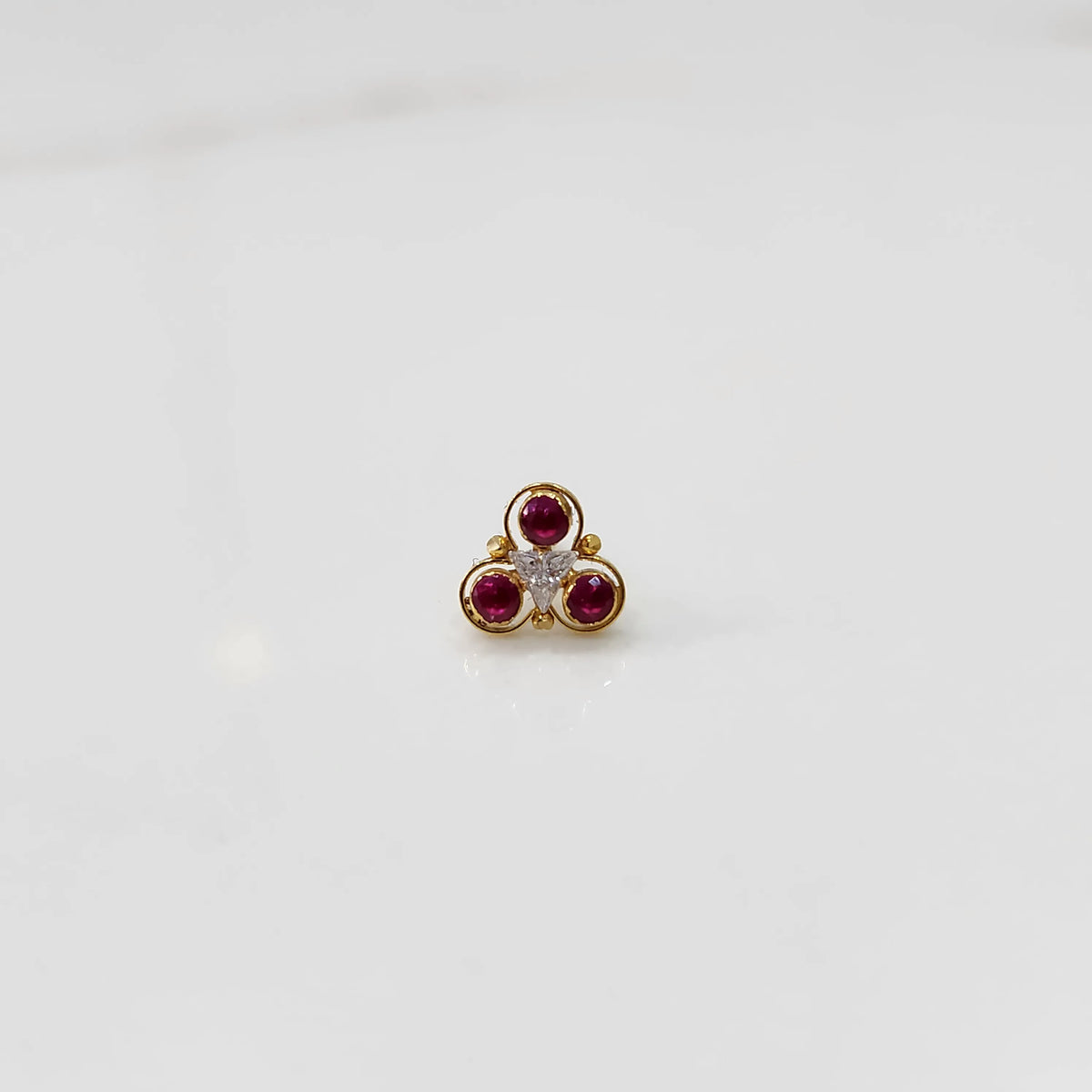 Close-up of gold three-stone ring featuring ruby and clear gemstones