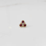 Close-up of gold three-stone ring featuring ruby and clear gemstones
