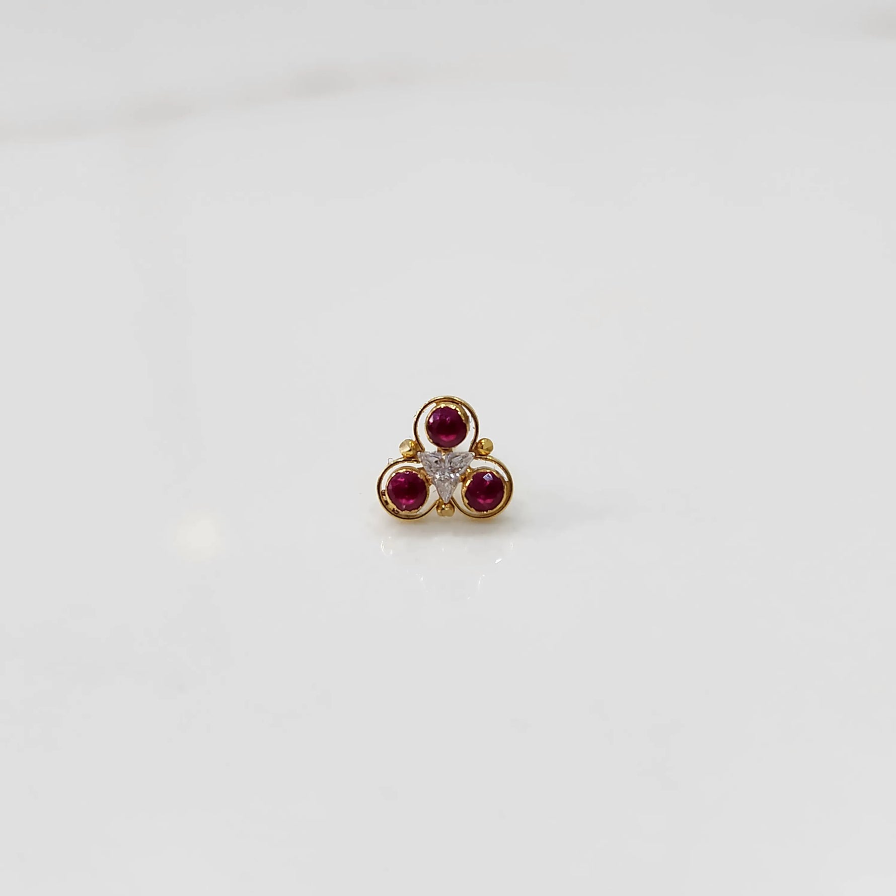 Close-up of gold three-stone ring featuring ruby and clear gemstones