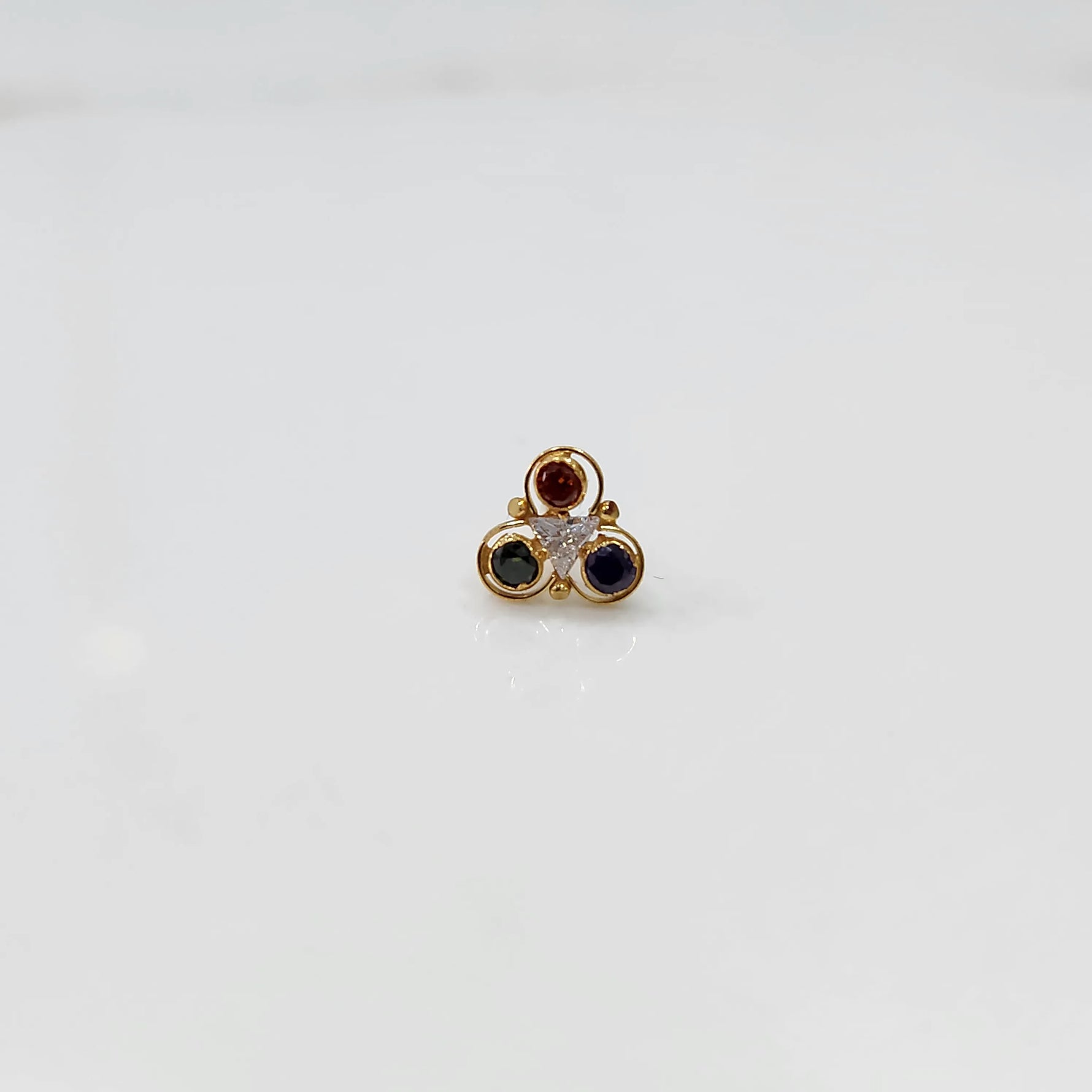 Top view of gold ring with ruby, sapphire and clear stone cluster
