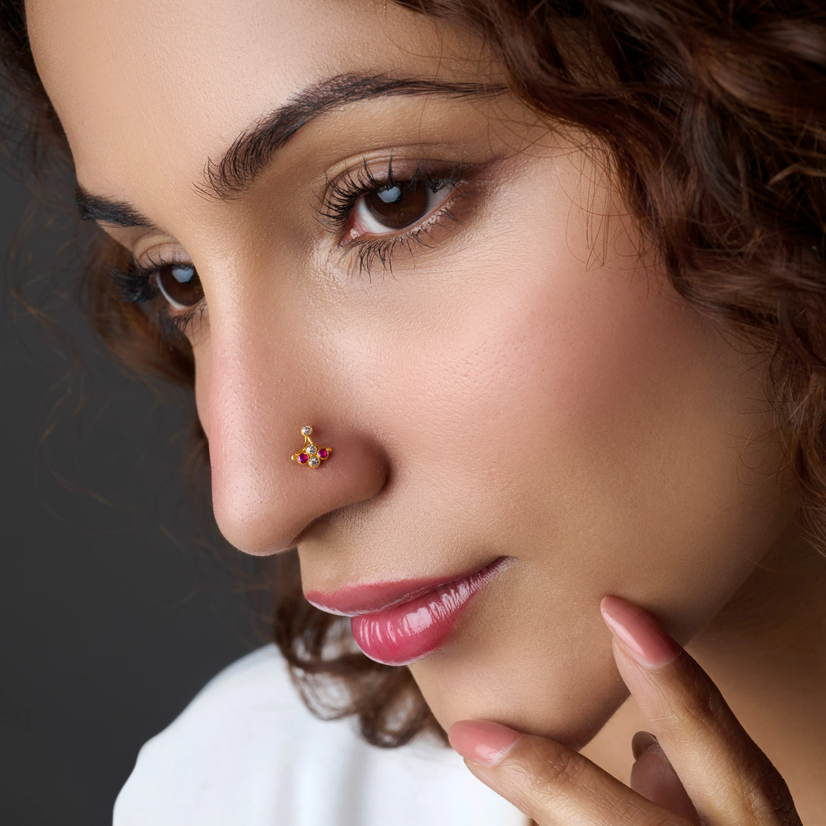Woman wearing a gold nose pin with trio stone design