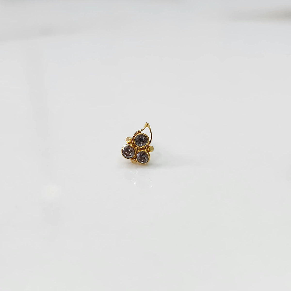 Close-up of gold statement ring with three gemstones and leaf-shaped design detail
