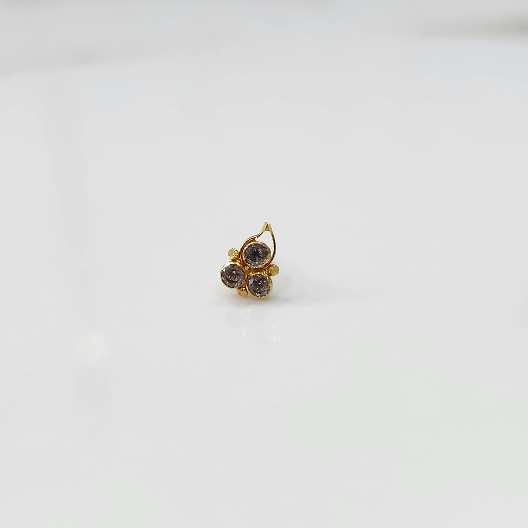 Close-up of gold statement ring with three gemstones and leaf-shaped design detail