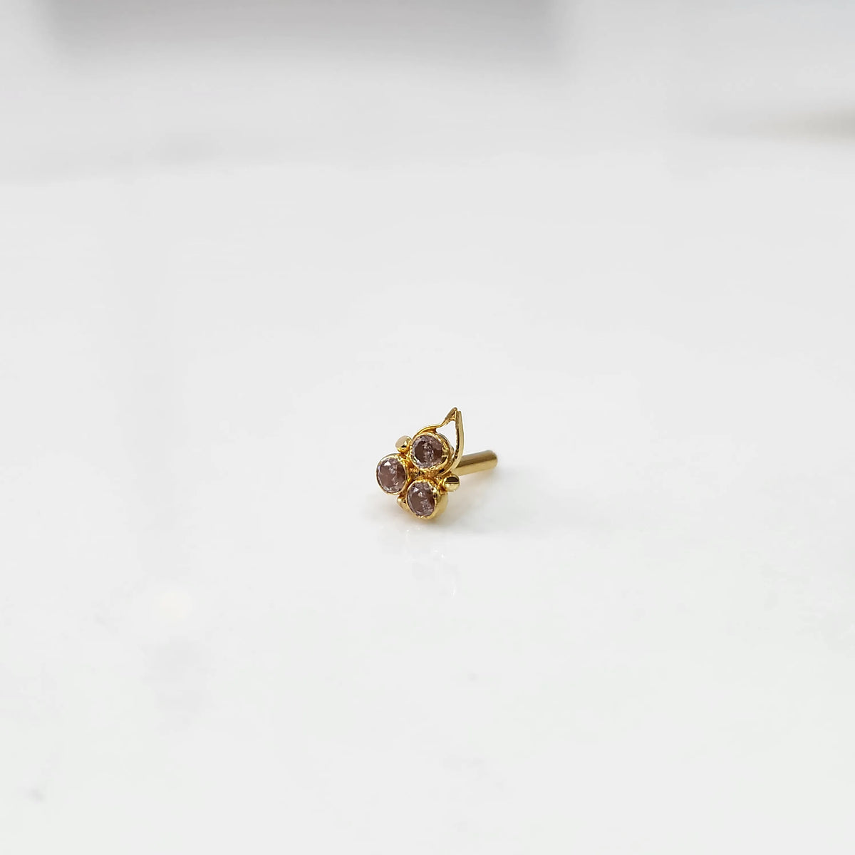 Gold statement ring with three purple-pink gemstones and leaf motif design