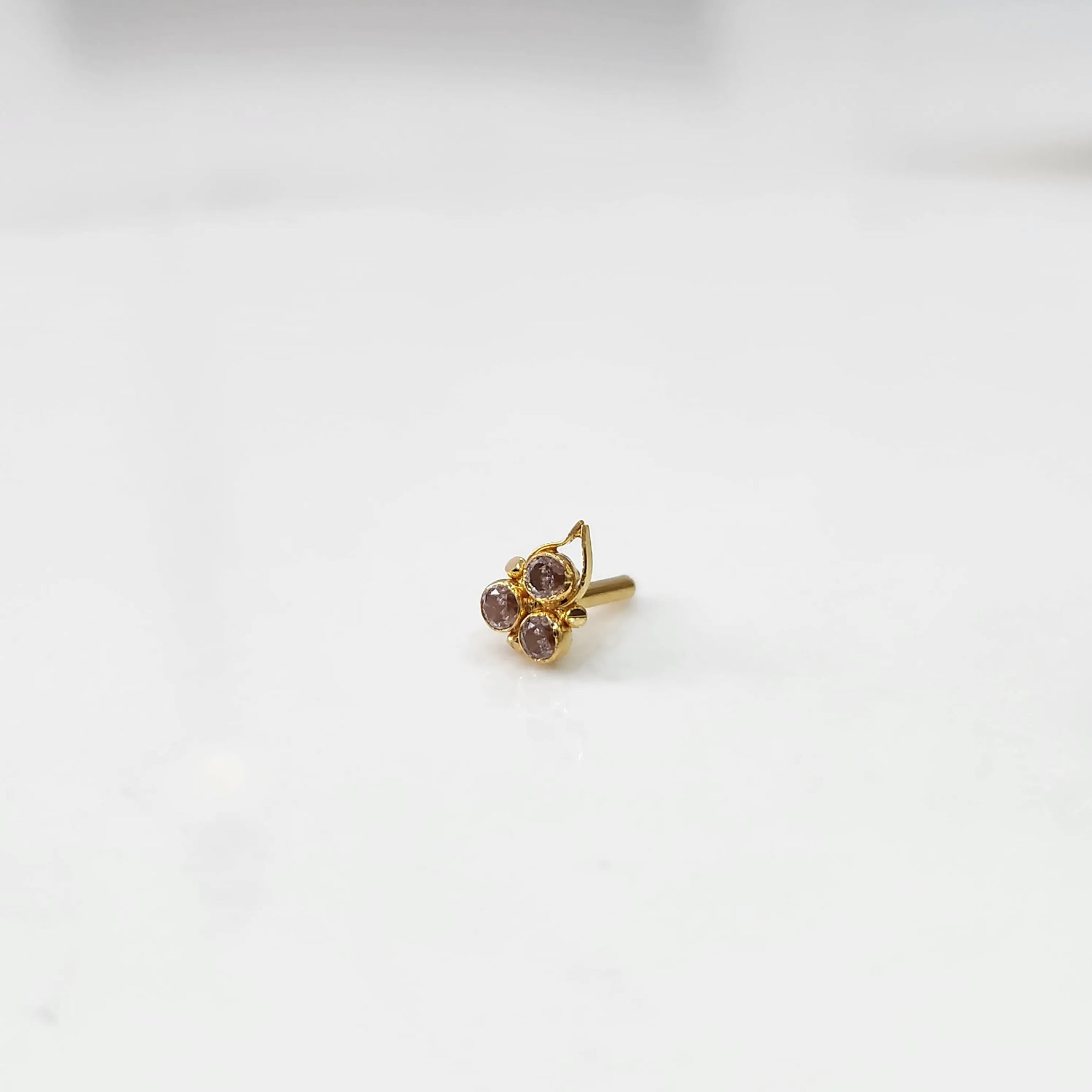 Gold statement ring with three purple-pink gemstones and leaf motif design