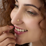 Woman wearing gold floral nose pin studded with white stones