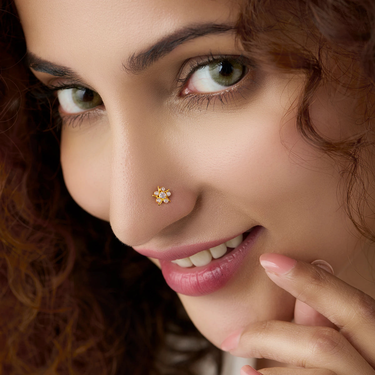 Woman wearing gold star flower nose pin with white stones