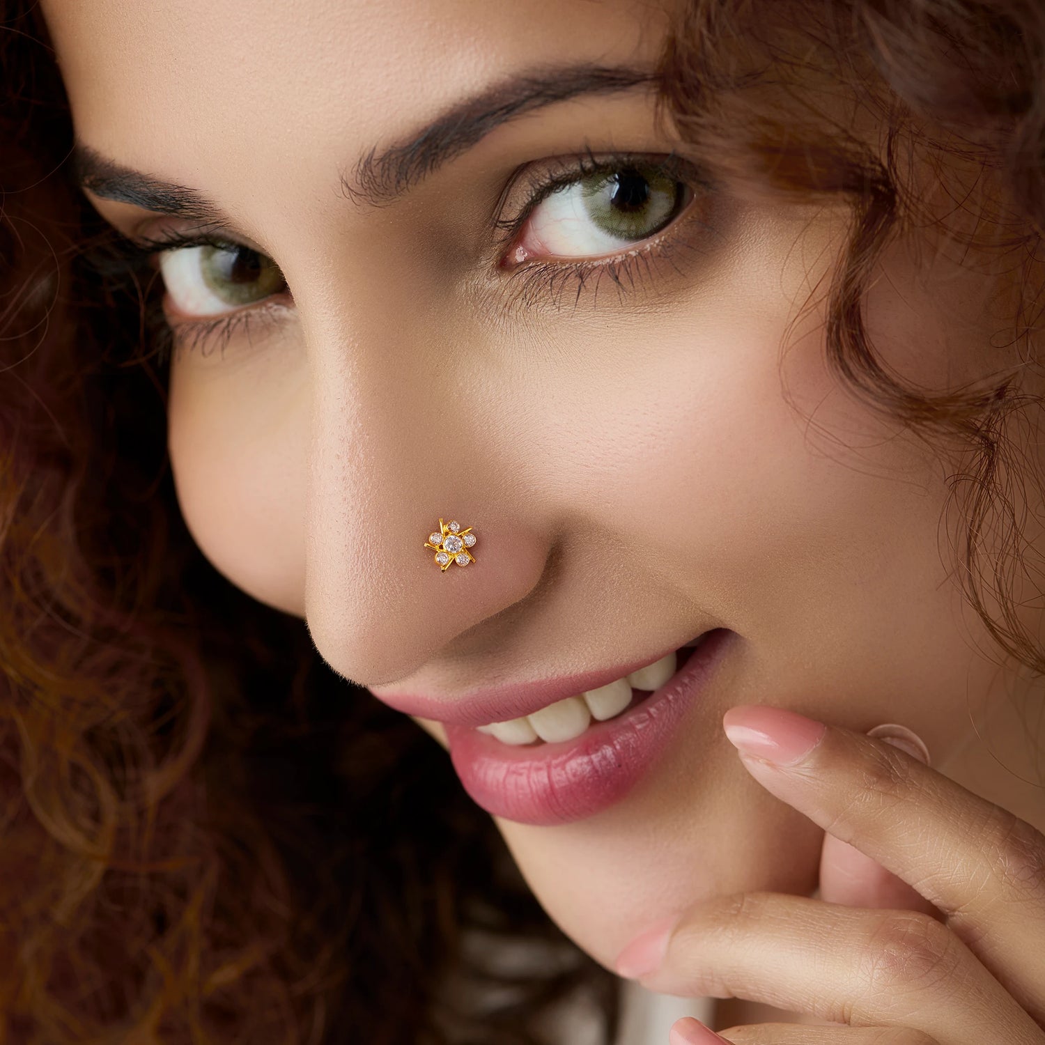 Woman wearing gold star flower nose pin with white stones