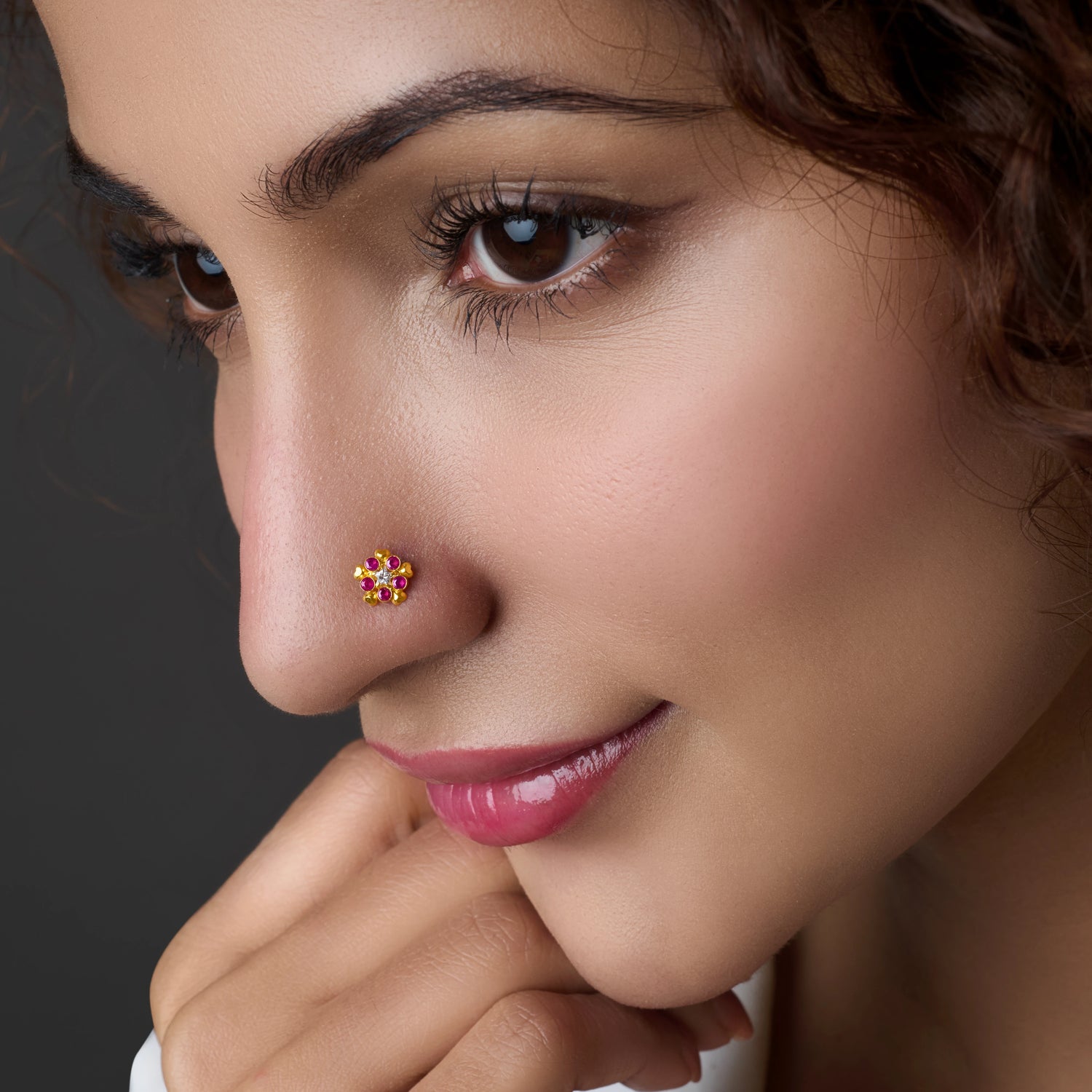 Woman wearing a floral gold nose pin with yellow and pink stones