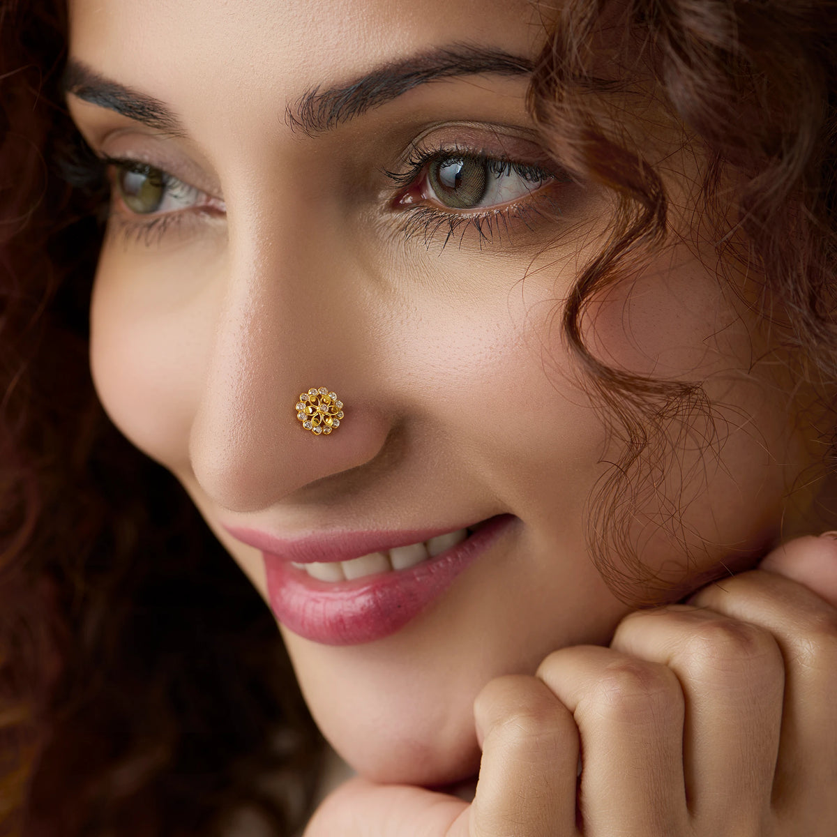 Woman wearing gold nose pin design with floral diamond pattern close up